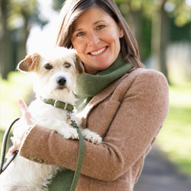 A woman smiling holding a small white terrier